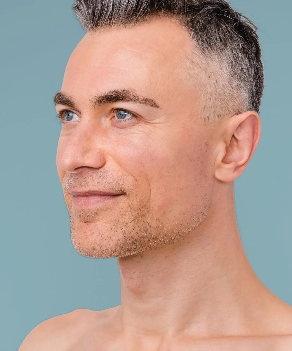 man in oblique view with black and grey hair smiling softly